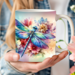 Custom name dragonfly flower mug. Vivid color sublimated mug design. Close-up of dragonfly mug being held by a woman, in her garden.